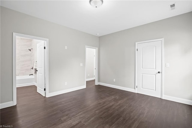 unfurnished bedroom featuring ensuite bathroom and dark wood-type flooring