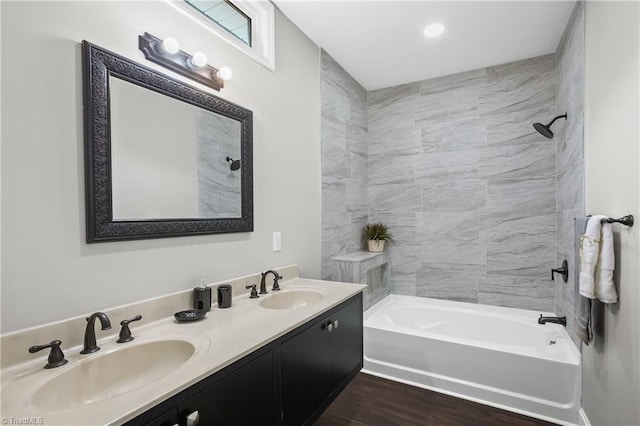 bathroom with hardwood / wood-style flooring, tiled shower / bath combo, and vanity