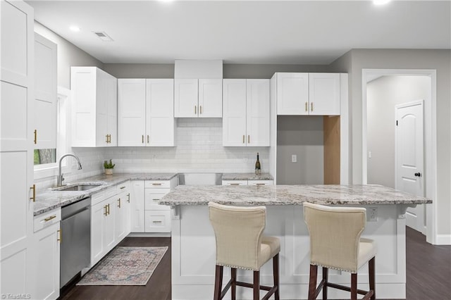 kitchen with white cabinetry, sink, a kitchen island, and stainless steel dishwasher