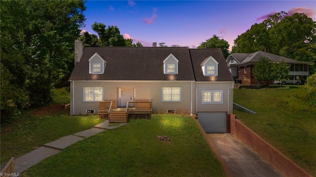 cape cod house featuring driveway, a garage, and a lawn