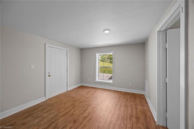 unfurnished bedroom with wood finished floors, baseboards, and a closet