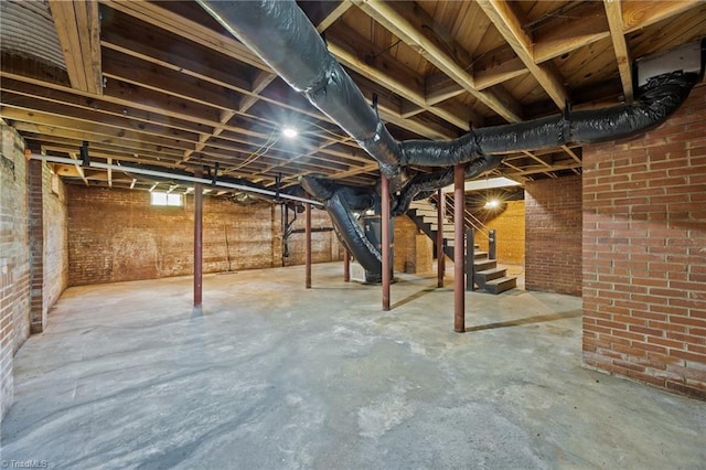 basement featuring stairway and brick wall
