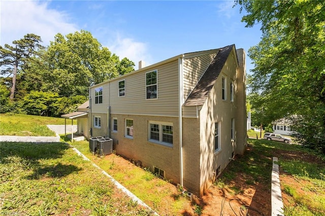 rear view of property with brick siding, cooling unit, and a chimney