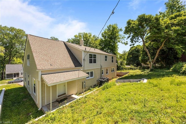 back of property featuring roof with shingles and a lawn