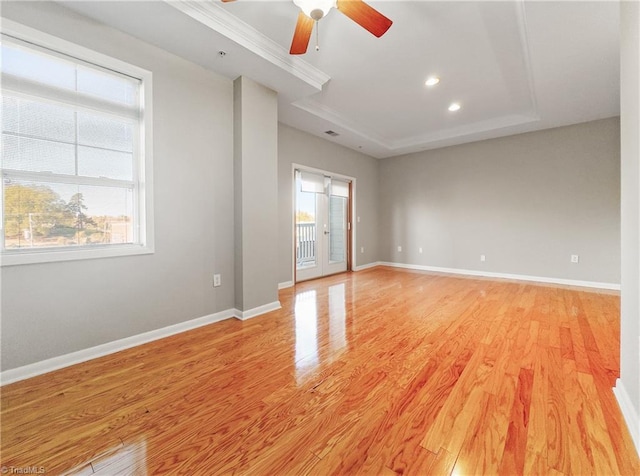 empty room featuring light wood-type flooring, a raised ceiling, and ceiling fan