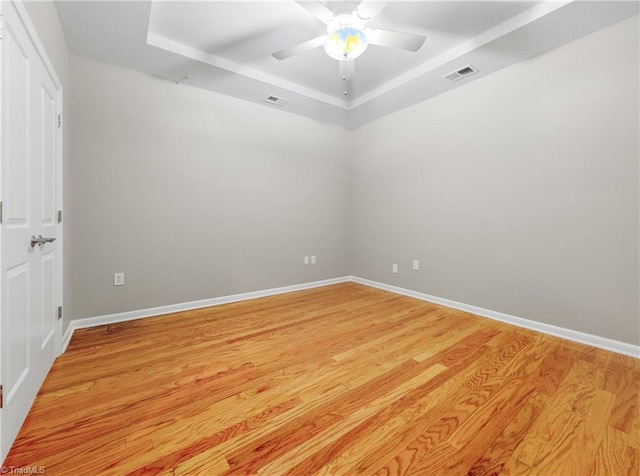 spare room featuring light hardwood / wood-style floors, a raised ceiling, and ceiling fan