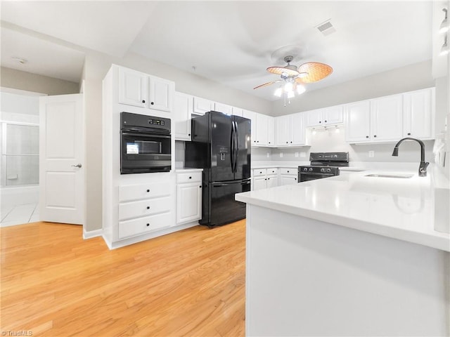 kitchen with black appliances, sink, light hardwood / wood-style flooring, white cabinetry, and kitchen peninsula