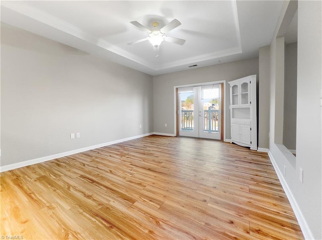 spare room with ceiling fan, a raised ceiling, french doors, and light hardwood / wood-style flooring