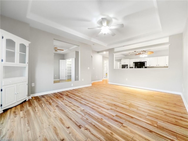 unfurnished living room with a raised ceiling and light wood-type flooring