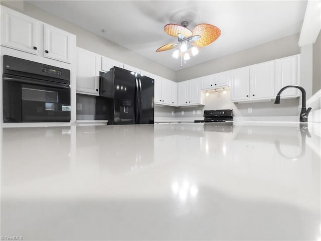 kitchen featuring black appliances, ceiling fan, white cabinetry, and sink