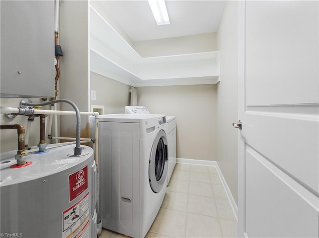 clothes washing area featuring light tile patterned flooring, gas water heater, and separate washer and dryer