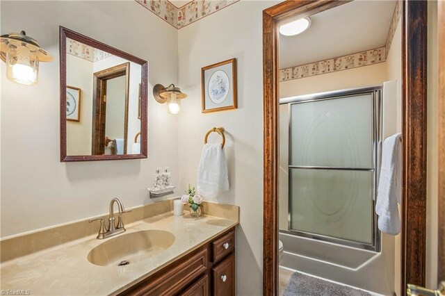 full bathroom with bath / shower combo with glass door, vanity, and toilet