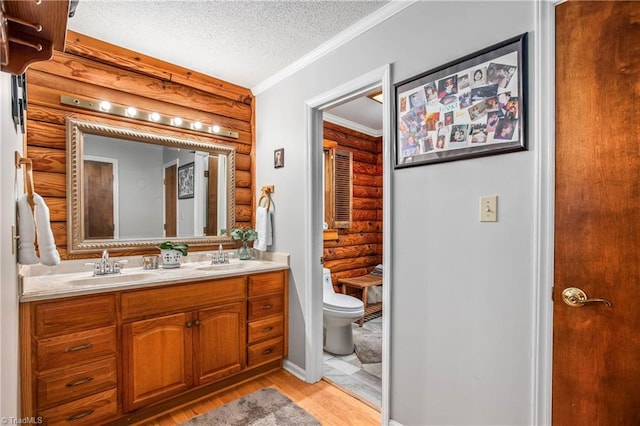 bathroom featuring crown molding, vanity, a textured ceiling, hardwood / wood-style flooring, and toilet