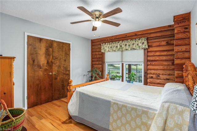 bedroom with light hardwood / wood-style floors, ceiling fan, a textured ceiling, and a closet