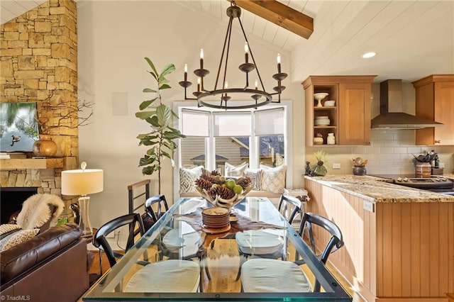 dining space featuring a notable chandelier, lofted ceiling with beams, a stone fireplace, and wood ceiling