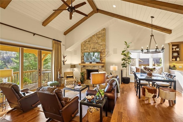 living room with beam ceiling, high vaulted ceiling, wood-type flooring, a fireplace, and ceiling fan with notable chandelier