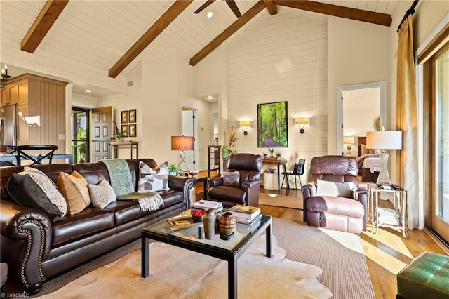 living room featuring beamed ceiling, light wood-type flooring, high vaulted ceiling, and plenty of natural light