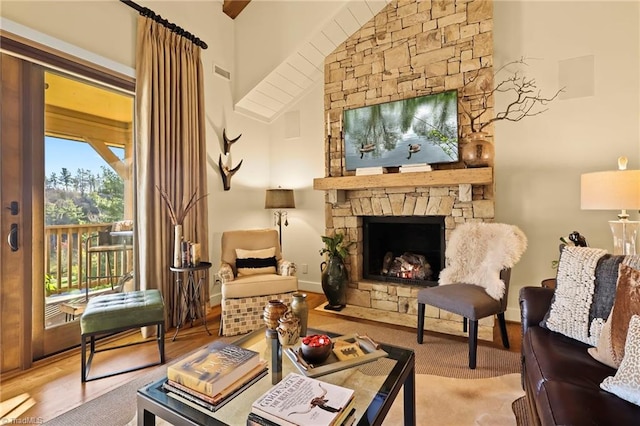 living area with a stone fireplace, hardwood / wood-style floors, and high vaulted ceiling