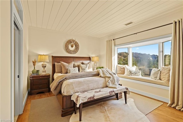 bedroom featuring light hardwood / wood-style flooring and wooden ceiling