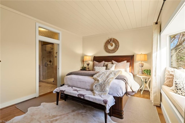 bedroom with light hardwood / wood-style floors, wooden ceiling, and connected bathroom