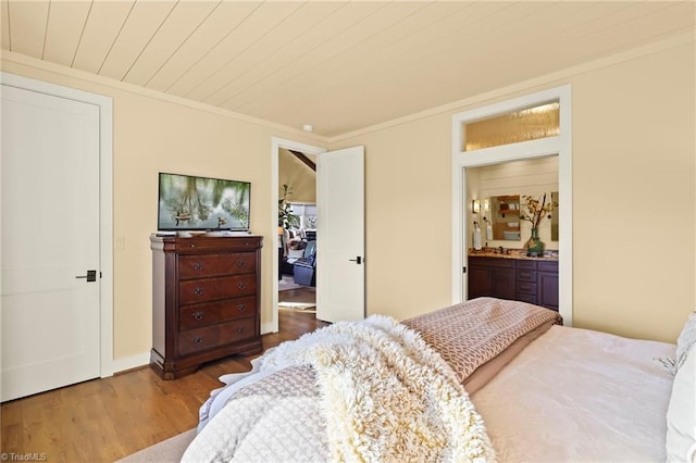 bedroom featuring hardwood / wood-style flooring, ensuite bath, ornamental molding, and wood ceiling