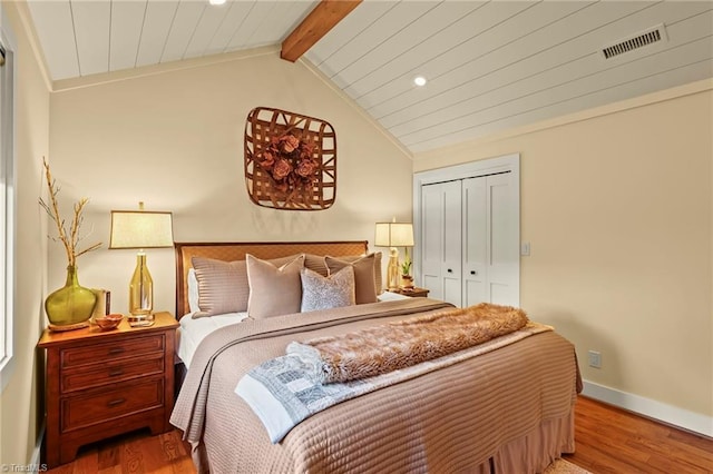 bedroom with vaulted ceiling with beams, wood-type flooring, and a closet