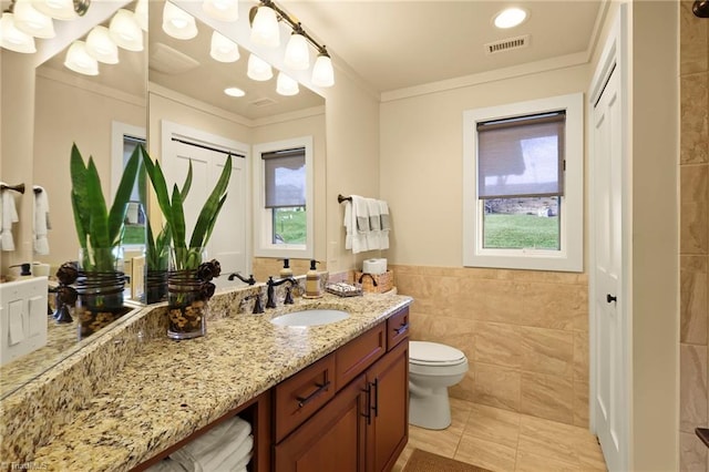 bathroom with ornamental molding, vanity, tile walls, tile patterned flooring, and toilet