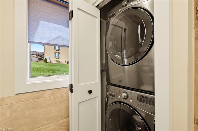 clothes washing area with tile walls and stacked washer and clothes dryer