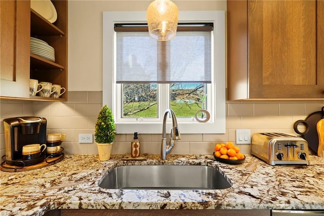 kitchen featuring backsplash, light stone countertops, and sink