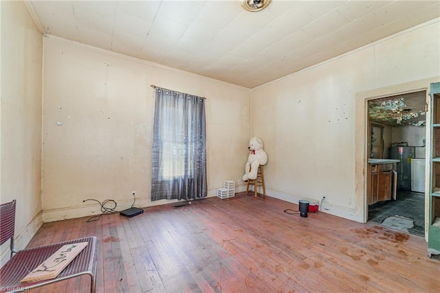 spare room with water heater, crown molding, and wood-type flooring