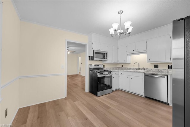 kitchen featuring sink, white cabinetry, hanging light fixtures, stainless steel appliances, and light hardwood / wood-style floors