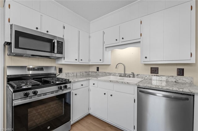 kitchen with white cabinetry, ornamental molding, appliances with stainless steel finishes, and sink