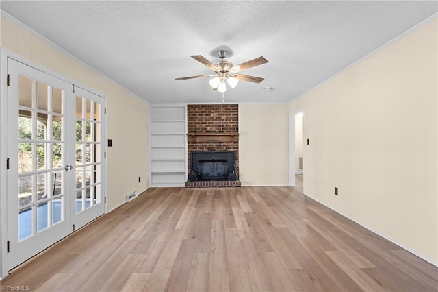 unfurnished living room featuring a brick fireplace, light hardwood / wood-style flooring, a textured ceiling, and ceiling fan