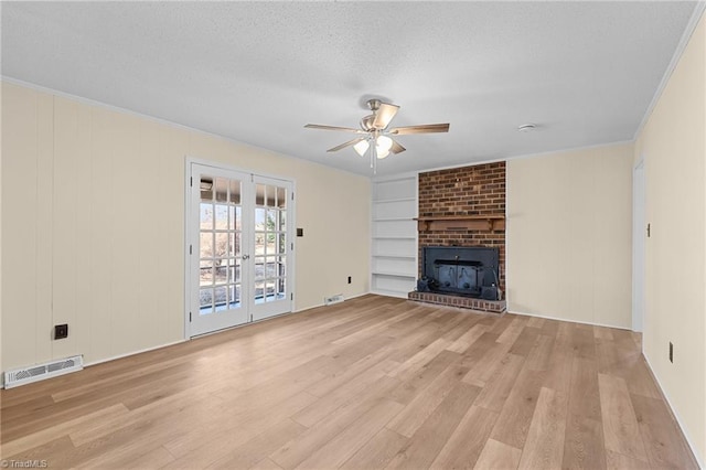 unfurnished living room featuring french doors, a brick fireplace, a textured ceiling, ceiling fan, and light hardwood / wood-style floors