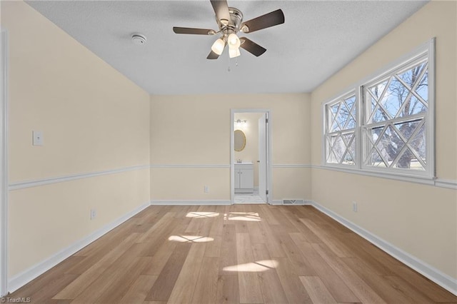 empty room with ceiling fan and light hardwood / wood-style flooring