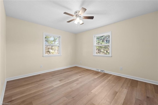 spare room with ceiling fan, a healthy amount of sunlight, and light hardwood / wood-style floors