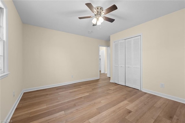 unfurnished bedroom featuring ceiling fan, a closet, and light wood-type flooring