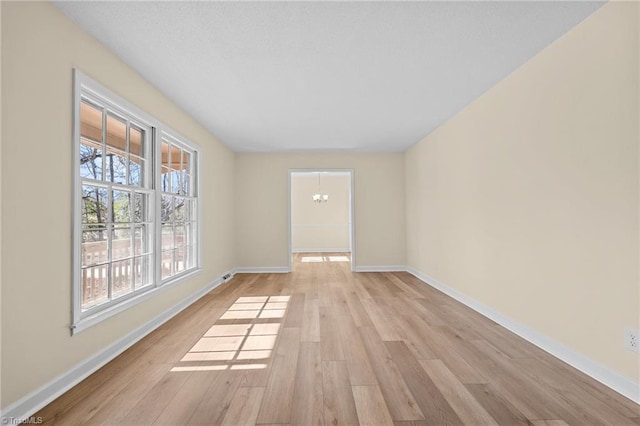 unfurnished room with an inviting chandelier and light hardwood / wood-style flooring