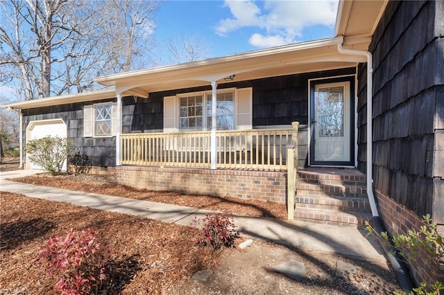 view of exterior entry featuring a porch and a garage