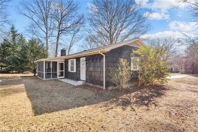 back of property with a sunroom and a yard