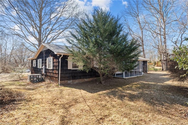 view of property exterior with a sunroom, a yard, and central AC unit