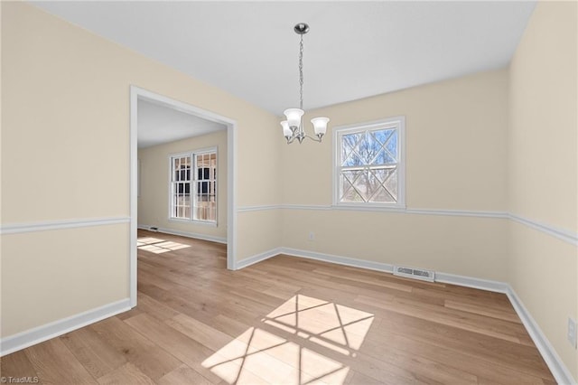 unfurnished dining area with an inviting chandelier and light hardwood / wood-style flooring