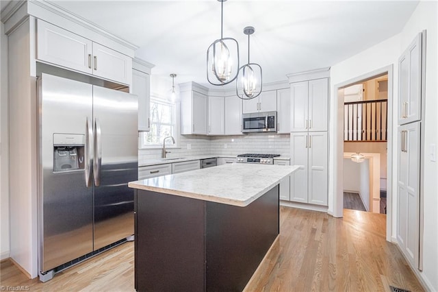 kitchen featuring hanging light fixtures, a center island, appliances with stainless steel finishes, and white cabinetry