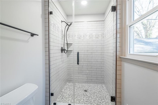 bathroom with a healthy amount of sunlight, an enclosed shower, and toilet