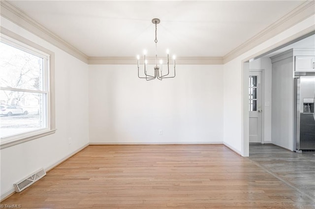 unfurnished dining area featuring light hardwood / wood-style floors, a chandelier, and crown molding