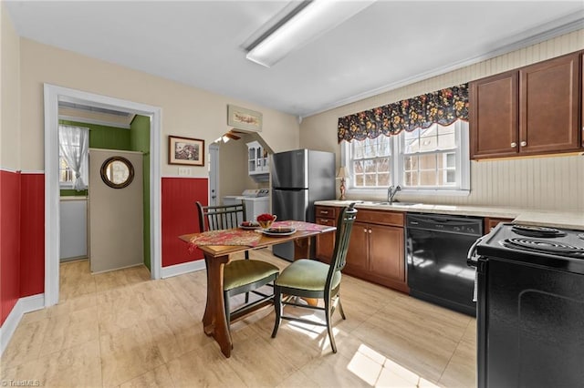 kitchen with a sink, black appliances, light countertops, and washer / dryer