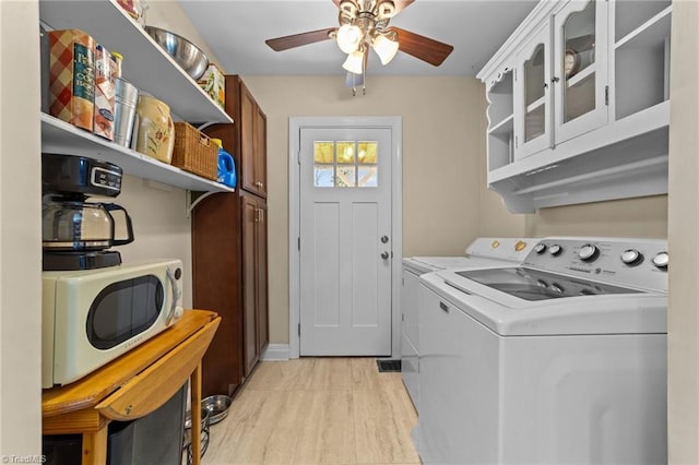 clothes washing area with washing machine and dryer, laundry area, ceiling fan, and light wood-style flooring