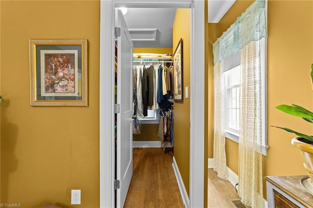 hall with visible vents, wood finished floors, attic access, and baseboards