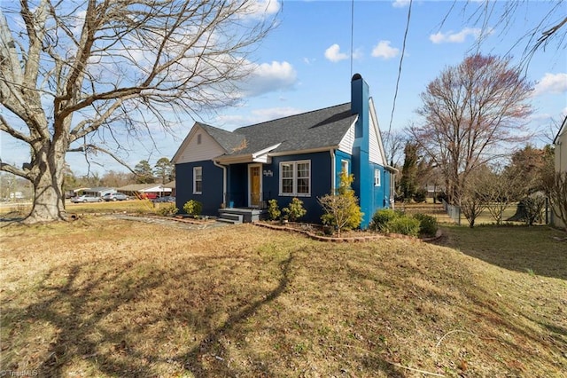 view of side of property with a chimney, fence, and a yard