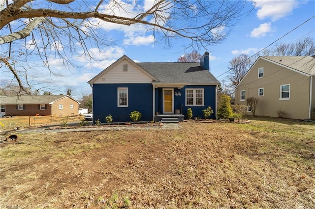 bungalow-style home featuring a chimney, fence, and a front yard